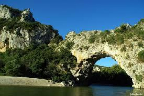 Arco naturale di pietra su un fiume vicino ad Arlebosc, Alvernia-Rodano-Alpi, Francia, immerso nel verde.