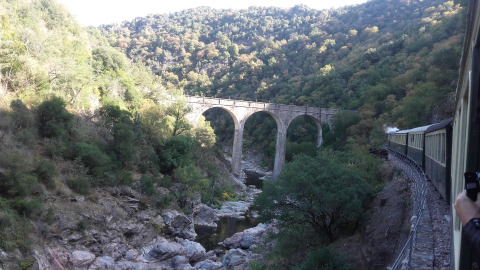 View from a vintage train crossing a scenic stone viaduct near Ushuaïa Villages Le Viaduc, France.