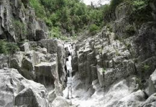 Rocky gorge with stream and lush vegetation at Ushuaïa Villages Le Viaduc, Auvergne-Rhône-Alpes, France.