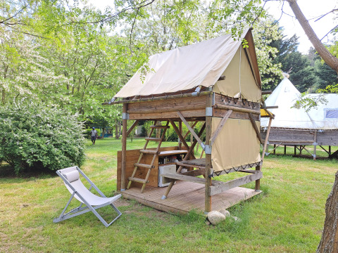 Bivak-tent op Campsite Ushuaïa Villages Le Viaduc in Frankrijk, omgeven door groene bomen en gras.