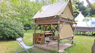 Tente bivouac au camping Ushuaïa Villages Le Viaduc en France, entourée d’arbres et d’herbe verte.