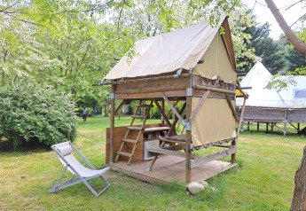 Bivouac tent at Campsite Ushuaïa Villages Le Viaduc in France, surrounded by lush green trees and grass.