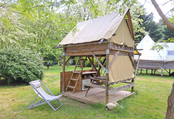 Bivak-tent op Campsite Ushuaïa Villages Le Viaduc in Frankrijk, omgeven door groene bomen en gras.