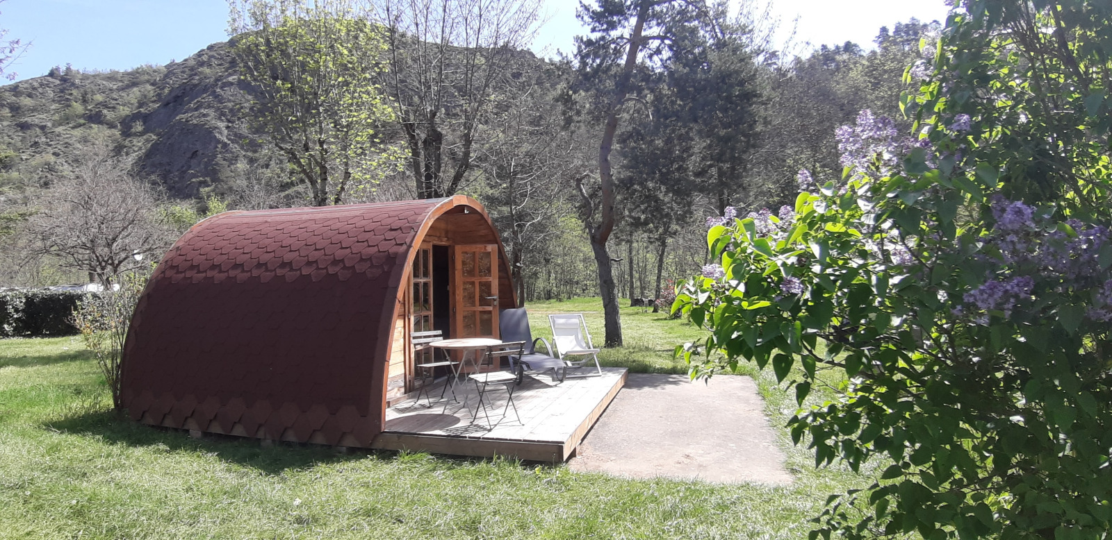 Pod met terras op Campsite Ushuaïa Villages Le Viaduc in Frankrijk, omgeven door bomen en natuur.