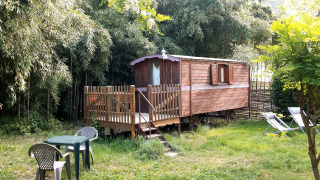 Tiny wagon cabin with porch and garden furniture at Campsite Ushuaïa Villages Le Viaduc in France.