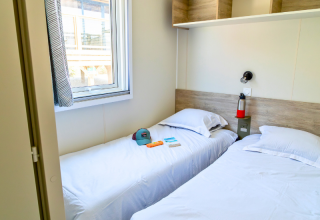 Camera con due letti singoli, finestra, mensole e oggetti personali nel Premium Mobile Home a Les Tamaris.