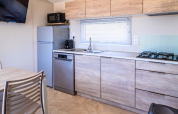 Modern kitchen in Premium Mobile Home at Campsite Les Tamaris, France, with wood cabinets and appliances.