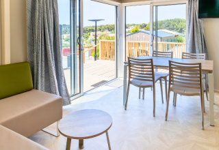 Interno luminoso di una casa mobile premium con zona pranzo e terrazza al campeggio Les Tamaris, Francia.