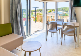 Interior luminoso de mobil home premium con comedor y terraza en el camping Les Tamaris, Francia.
