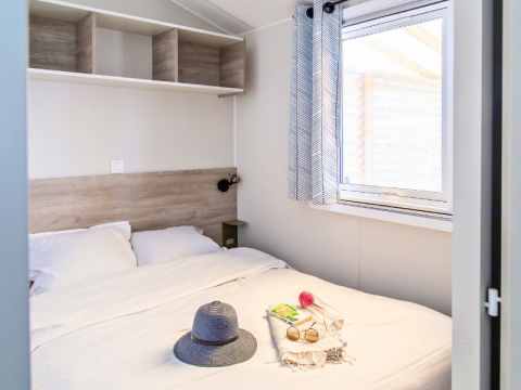 Camera da letto nel Premium Mobile Home al campeggio Les Tamaris, letto grande e finestra luminosa.