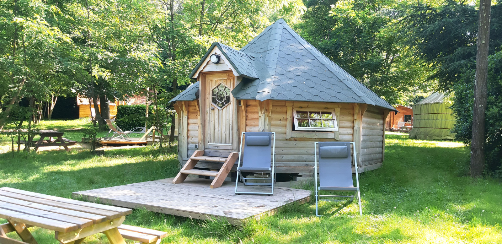 Finse kota blokhut met twee ligstoelen ervoor, omgeven door bomen op Ushuaïa Villages Le Viaduc camping.