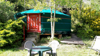 Une yourte verte à porte rouge décorée, entourée de verdure et de mobilier de jardin à Ushuaïa Villages Le Viaduc.