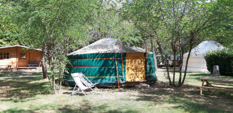 Tenda yurta al campeggio Ushuaïa Villages Le Viaduc in Francia, immersa tra alberi e area relax.
