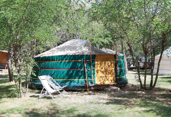 Yourte au camping Ushuaïa Villages Le Viaduc en France, entourée d’arbres et de mobilier de jardin.