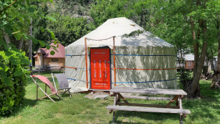 WOOD Yurt at Campsite Ushuaïa Villages Le Viaduc, France, with wooden picnic table and chairs outside.