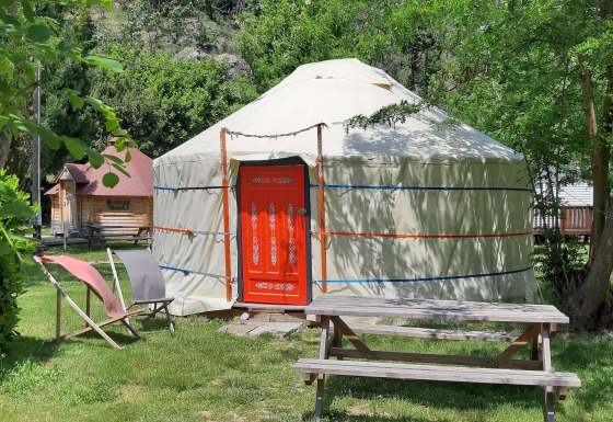 Yurta WOOD al campeggio Ushuaïa Villages Le Viaduc, Francia, con tavolo da picnic e sedie all’esterno.