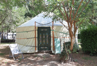 Traditional yurt tent at Campsite Ushuaïa Villages Le Viaduc, France, surrounded by green trees.