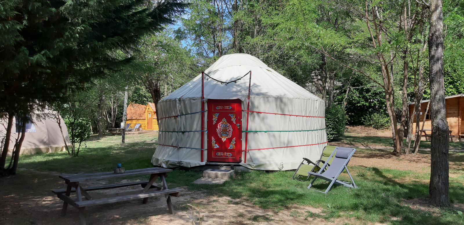 Foto van een traditionele yurt op Ushuaïa Villages Le Viaduc camping in Frankrijk, omgeven door bomen.