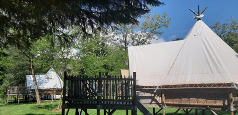 Tipi su piattaforme di legno al Tipi Lodge del campeggio Ushuaïa Villages Le Viaduc, immersi nel verde in Francia.