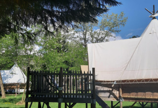 Tipi su piattaforme di legno al Tipi Lodge del campeggio Ushuaïa Villages Le Viaduc, immersi nel verde in Francia.