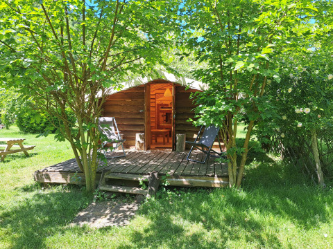 Log cabin with a porch and chairs surrounded by trees at Campsite Ushuaïa Villages Le Viaduc, France.