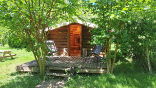 Log cabin with a porch and chairs surrounded by trees at Campsite Ushuaïa Villages Le Viaduc, France.