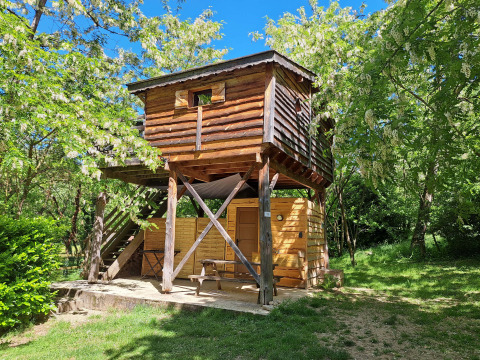 Cabane perchée du camping Ushuaïa Villages Le Viaduc en France, entourée de verdure et de ciel bleu.