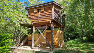 Cabane perchée du camping Ushuaïa Villages Le Viaduc en France, entourée de verdure et de ciel bleu.