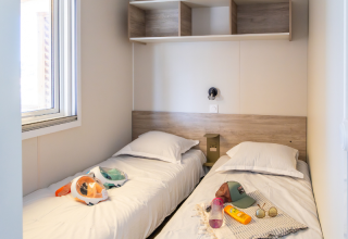 To enkeltsenge i et lyst værelse med vindue, sengetøj og strandtilbehør i Premium Mobile Home, Les Tamaris.