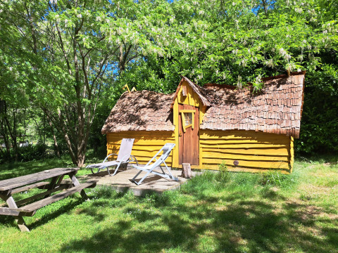 The Magic hut, a yellow wooden tiny house at Campsite Ushuaïa Villages Le Viaduc in France, in a forest.