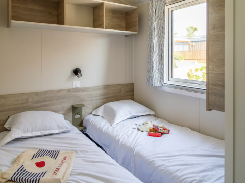 To enkeltsenge i et lyst chaletværelse på Premium Mobile Home «hilly location» på Campsite Les Tamaris, Frankrig.