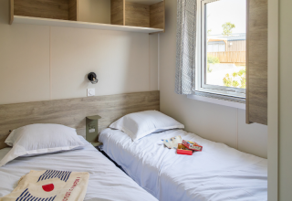 To enkeltsenge i et lyst chaletværelse på Premium Mobile Home «hilly location» på Campsite Les Tamaris, Frankrig.