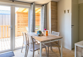 Luminoso comedor en Premium Mobile Home en Campsite Les Tamaris, Francia, con terraza de madera y muebles modernos.