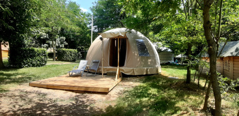 Wigwam dome at Campsite Ushuaïa Villages Le Viaduc in France, set among trees with a wooden deck.