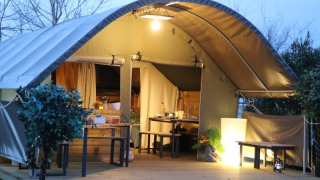 Tente safari Kibo au camping Ushuaïa Villages Le Viaduc en France, éclairée avec terrasse en bois.
