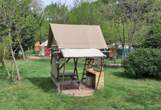 Bivouac-safaritent op Campsite Ushuaïa Villages Le Viaduc in Frankrijk, omgeven door gras en bomen.