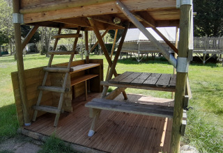 Houten terras en picknicktafel van de Bivouac-tent op Ushuaïa Villages Le Viaduc camping in Frankrijk.