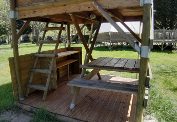 Terrazza in legno e tavolo da picnic della tenda Bivouac al campeggio Ushuaïa Villages Le Viaduc in Francia.