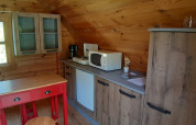 Cozy wooden kitchenette in a pod at Ushuaïa Villages Le Viaduc campsite with a red table and microwave.