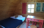 Cozy wooden pod interior with bed, table and cabinets at Ushuaïa Villages Le Viaduc campsite in France.