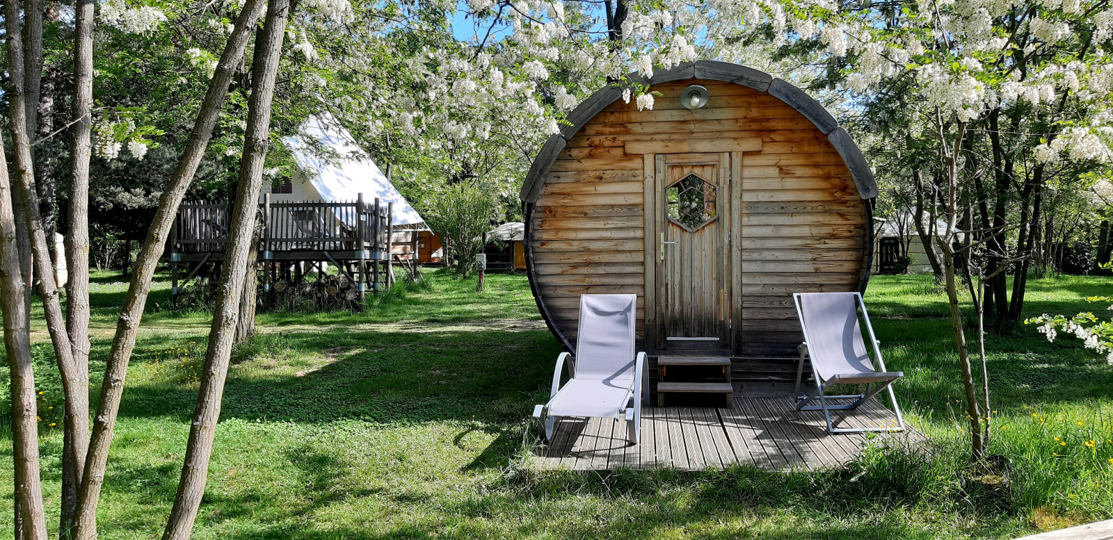 Een gezellig vatvormig pod met ligstoelen vooraan op Ushuaïa Villages Le Viaduc Camping in Frankrijk.