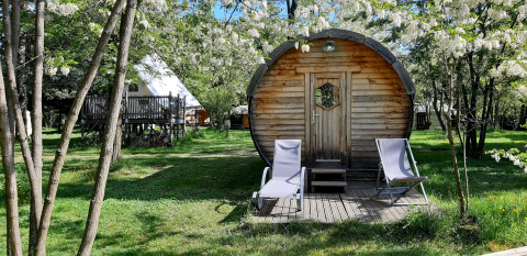 A cozy barrel-shaped pod with deck chairs outside at Ushuaïa Villages Le Viaduc Campsite in France.