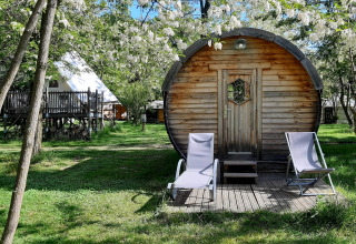 Een gezellige tonvormige pod met loungestoelen buiten bij Ushuaïa Villages Le Viaduc in Frankrijk.