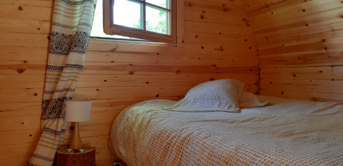 Knusse houten pod slaapkamer met bed en venster in 'Barrel' pod bij Ushuaïa Villages Le Viaduc, Frankrijk.