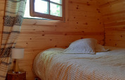 Cozy wooden pod bedroom with bed, pillows, lamp, and window at 'Barrel', Ushuaïa Villages Le Viaduc, France.