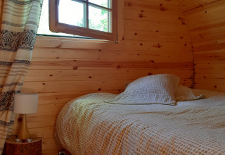 Knusse houten pod slaapkamer met bed en venster in 'Barrel' pod bij Ushuaïa Villages Le Viaduc, Frankrijk.