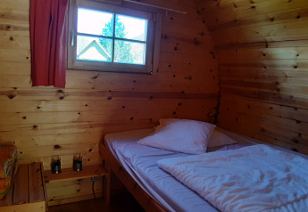 Indvendig visning af træ-pod 'Barrel' med enkeltseng og vindue på Ushuaïa Villages Le Viaduc campingplads i Frankrig.