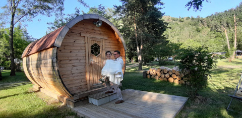 Een koppel bij de Barrel-pod op Campsite Ushuaïa Villages Le Viaduc in Frankrijk, tussen het groen.