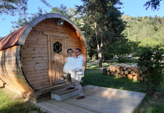 Een koppel bij de Barrel-pod op Campsite Ushuaïa Villages Le Viaduc in Frankrijk, tussen het groen.