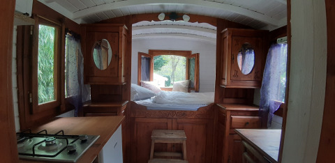 Interno della Tiny wagon al Campeggio Ushuaïa Villages Le Viaduc in Francia, con letto e cucina.